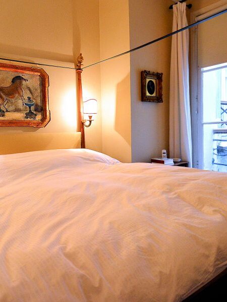 The master bedroom (4-poster, queen-sized bed) has windows overlooking the gallery-lined streets of Saint-Germain, Paris.