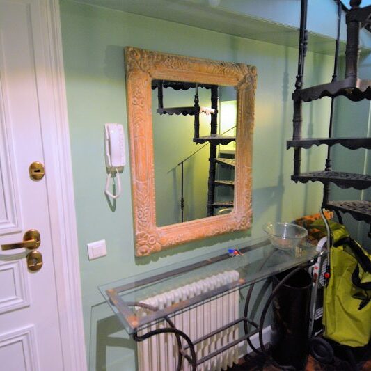 A wrought iron spiral staircase leads to the apartment's upper floor.