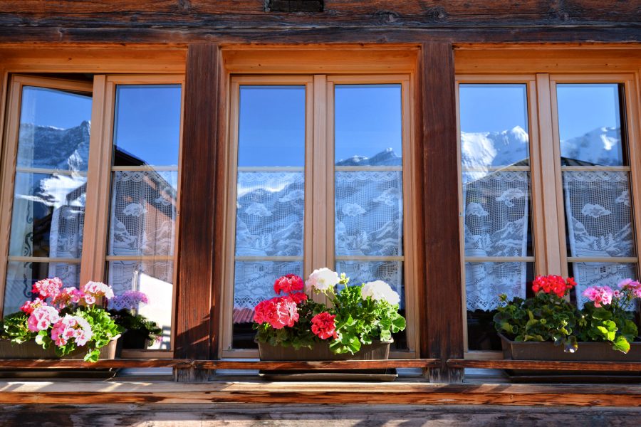 THE BERNESE OBERLAND - The Bernese Alps reflected in the geranium-jeweled windows of a traditional alpine chalet.