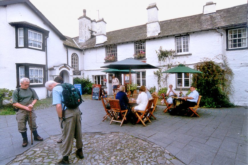 Lake District: Walkers and tea takers gather by Beatrix Potter Gallery on Hawkshead village square. Photo copyright Home At First.