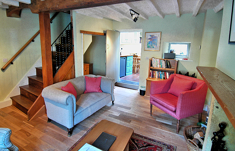 Living Room with fireplace, kitchen access, and stairs. Photo copyright Home At First.