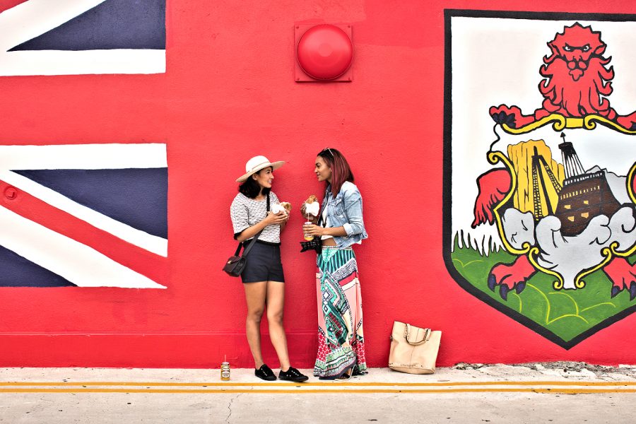 Hamilton: 2 women lunching on fish sandwiches by wall art. Bermuda Tourism Authority photo.