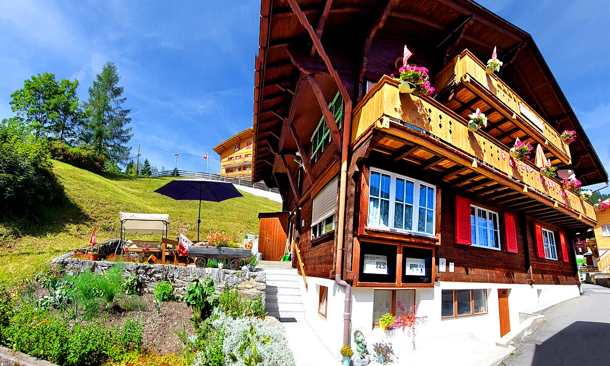 Chalet Silberhorn: exterior showing garden, patio, balconies, and steps to the house entry. Photo © Home At First.